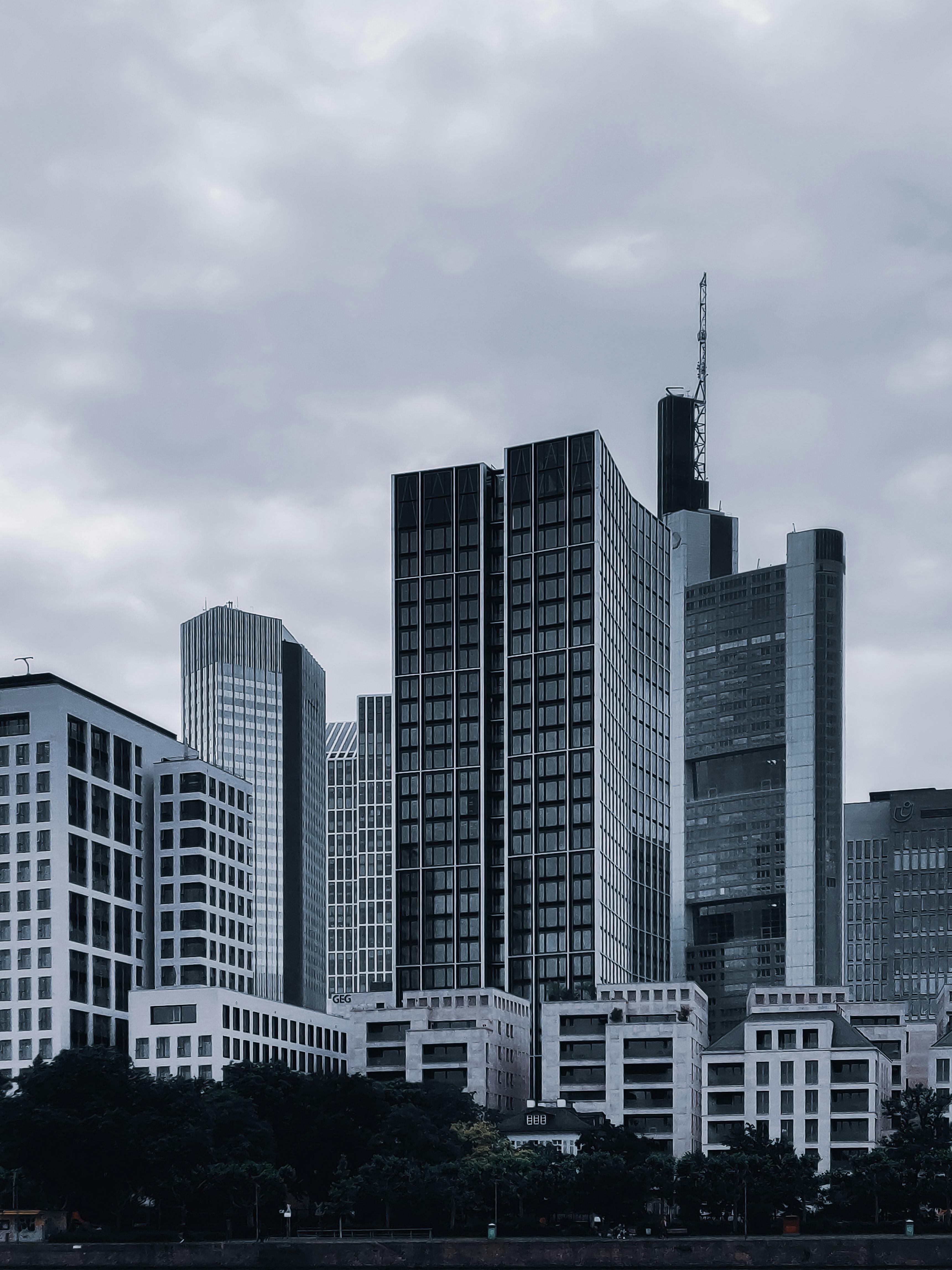 现代城市街道上，矗立着各种黑色和白色的当代建筑与摩天大楼，它们拥有玻璃外墙，映衬着阴云密布的天空