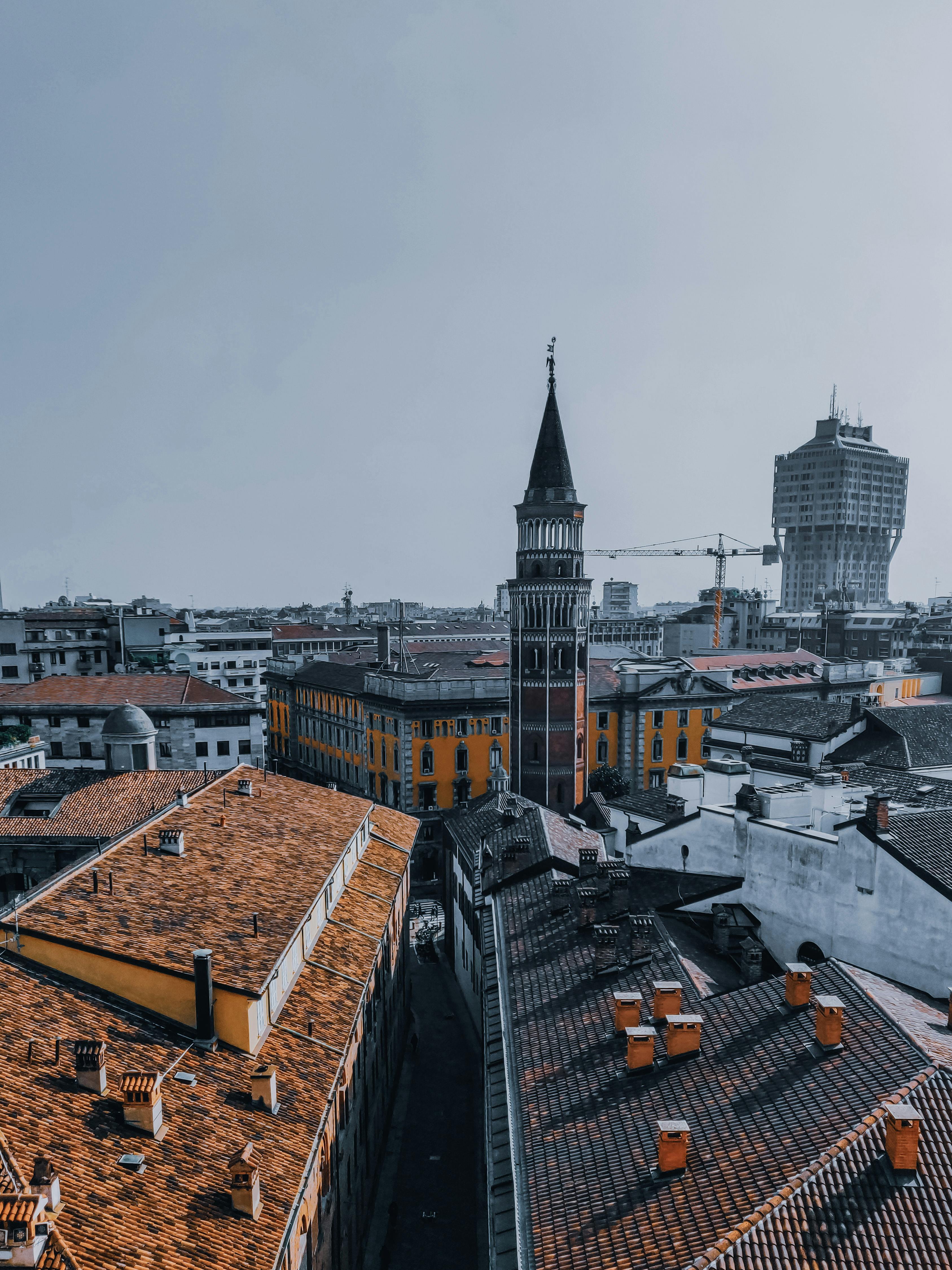 bell tower of aged roman catholic church near buildings on city street