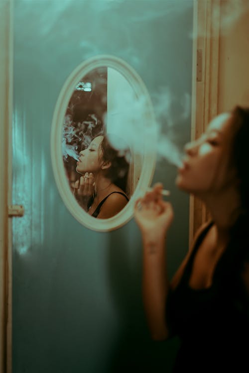 Free A Reflection of a Woman in the Mirror Smoking a Cigarette Stock Photo
