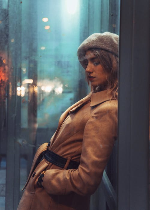 Woman in Brown Coat Standing Near Glass Wall
