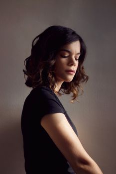 A serene and introspective portrait of a young woman in soft lighting.