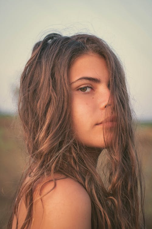 Beautiful woman with long hair standing on blurred field