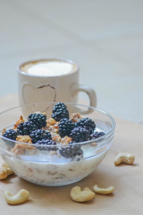 Free Glass bowl of granola with blackberries, cashews, and a cup of coffee. Stock Photo