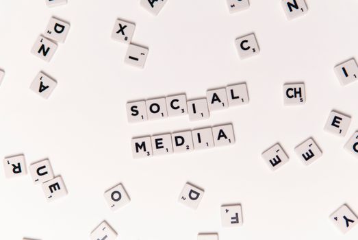 Flat lay of letter tiles spelling Social Media with scattered white tiles on a surface.
