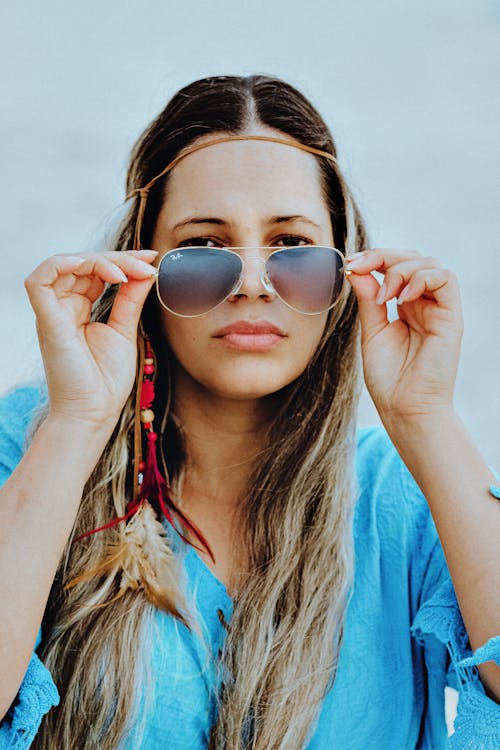 Woman in Blue Shirt Holding Sunglasses 