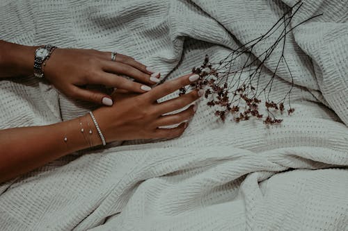 Hands with White Nail Polish Touching Dried Flowers