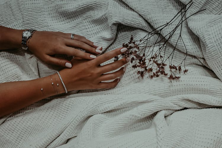 Hands With White Nail Polish Touching Dried Flowers