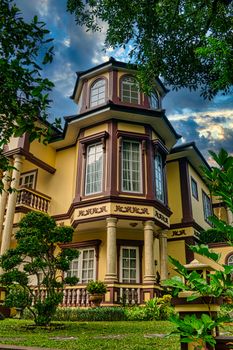 Beautiful vintage mansion surrounded by lush green gardens in Banten, Indonesia featuring classic architectural details.