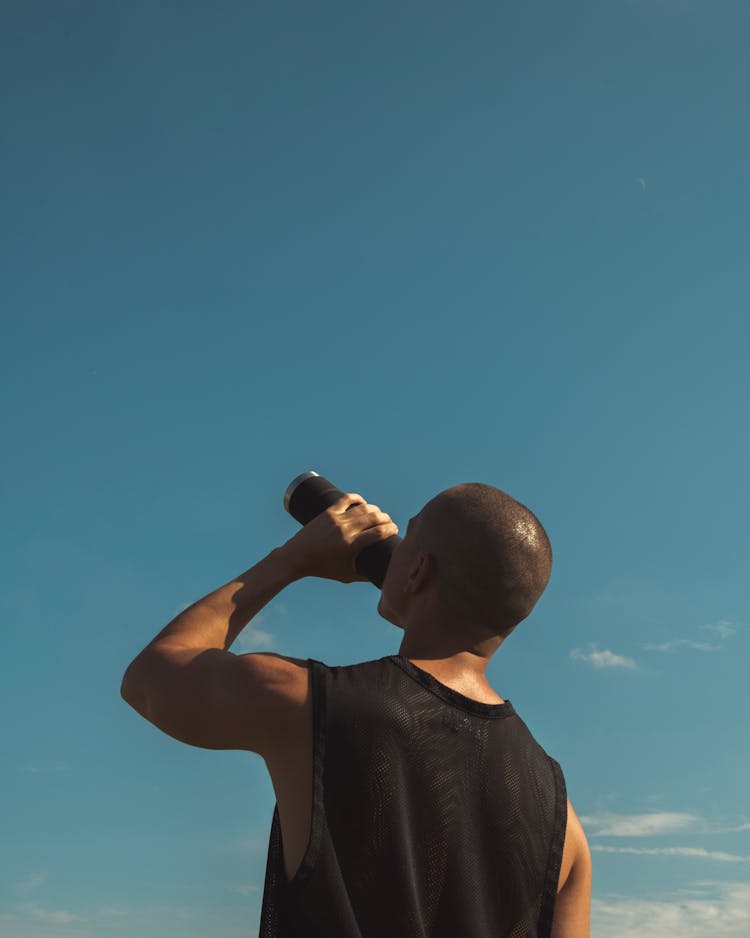 Man Drinking From Black Water Tumbler Under Blue Sky