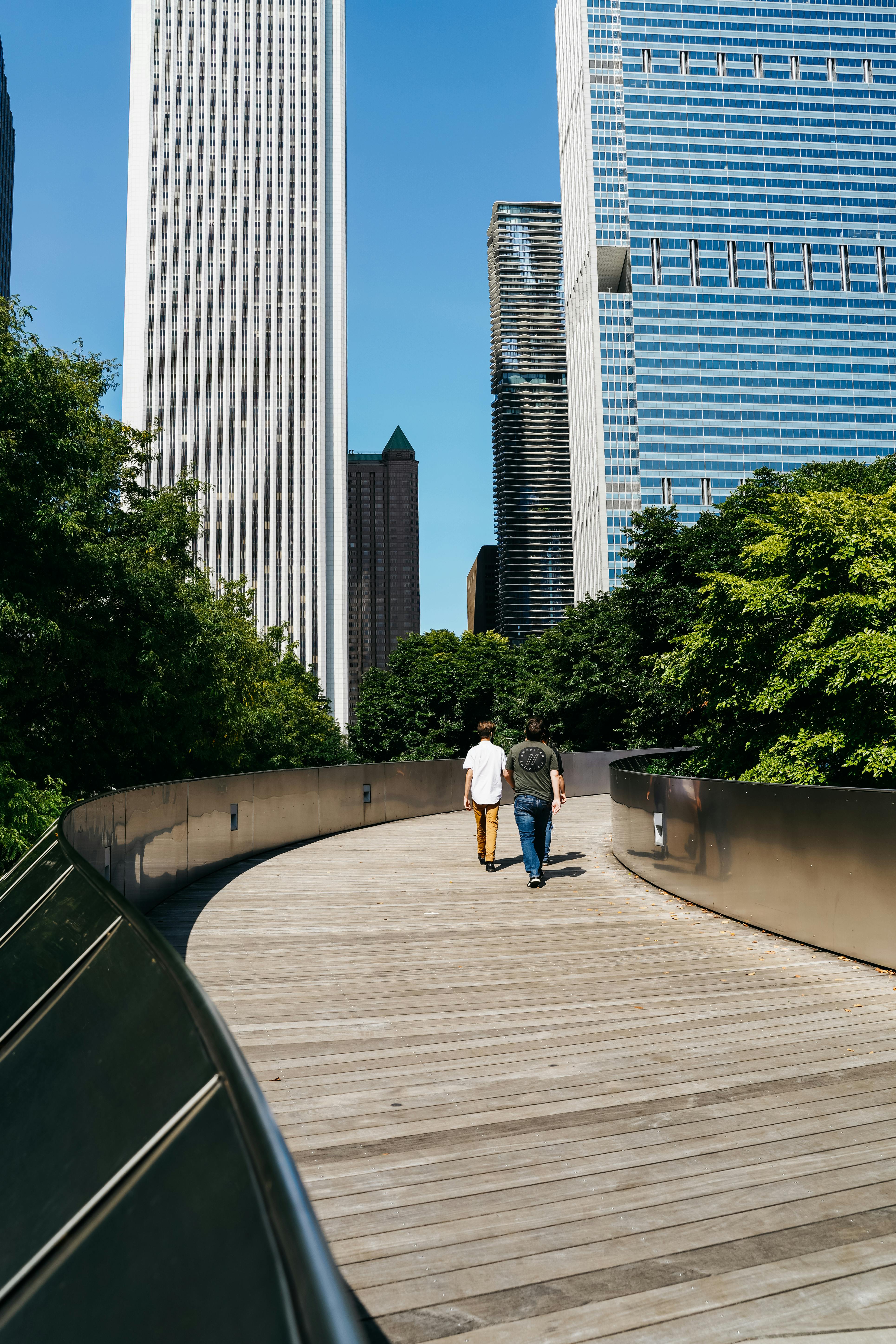 unrecognizable people walking on boardwalk towards city skyscrapers