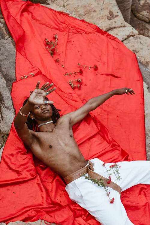 Photo of a Shirtless Man Lying on a Red Cloth