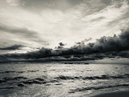 A Grayscale Photo of the Sea Under a Cloudy Sky