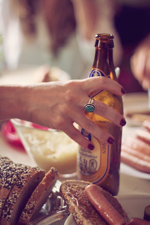 Person Holding Brown Labeled Bottle