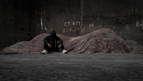 Man in a Black Hoodie Sitting on the Ground