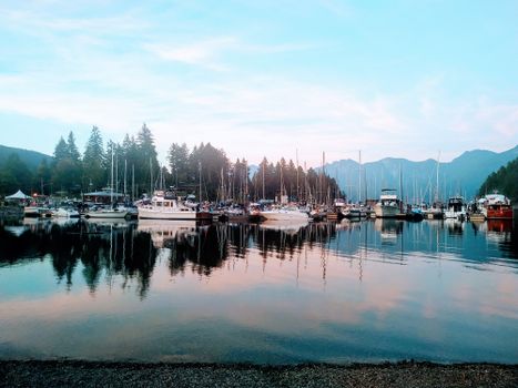Peaceful harbor view with boats reflecting on calm water in BC, Canada during sunset.