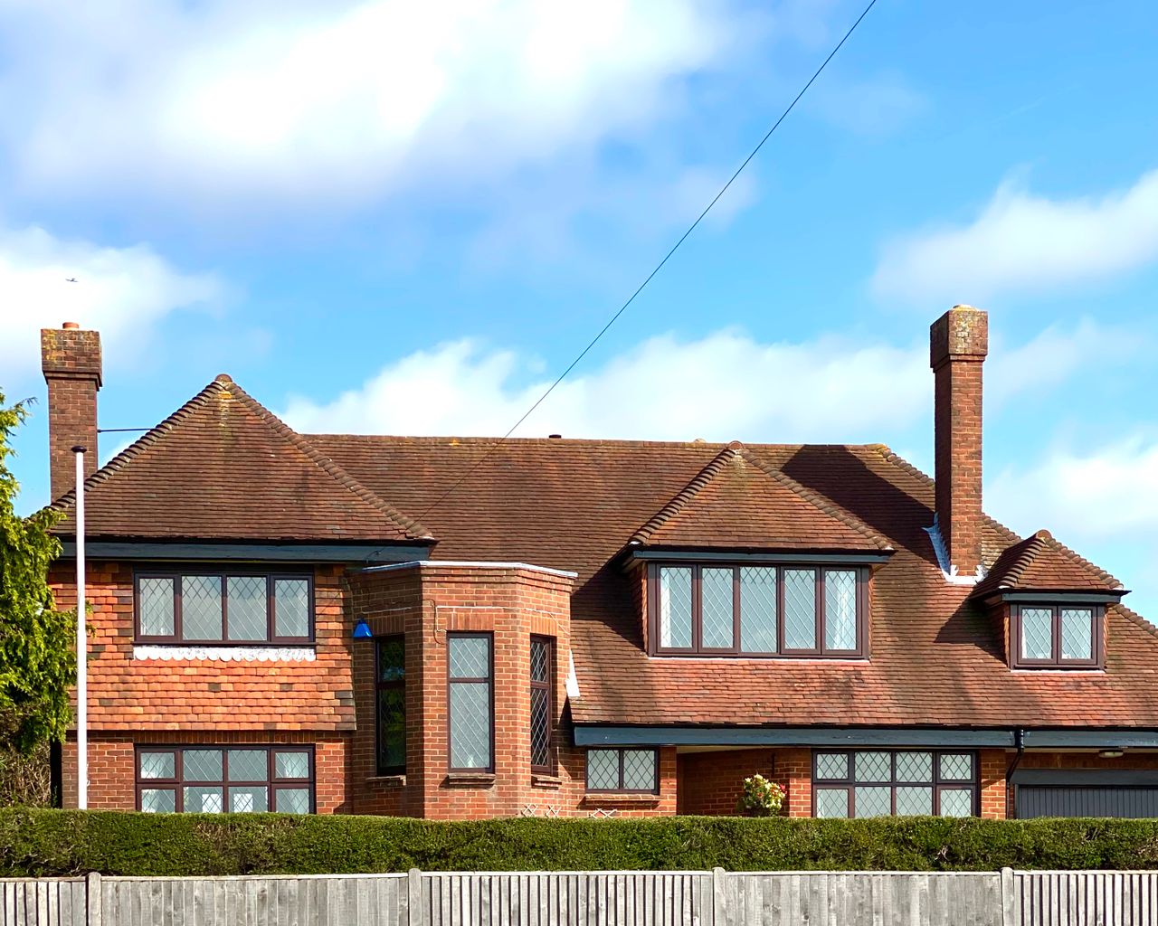 Red-brick 1930s-style suburban house with hipped roof and bay