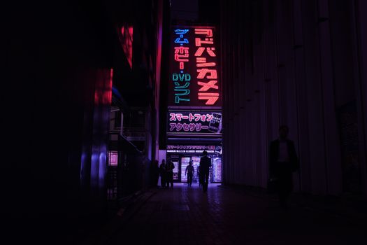 Colorful neon signs illuminate a busy Tokyo street at night, showcasing urban life.