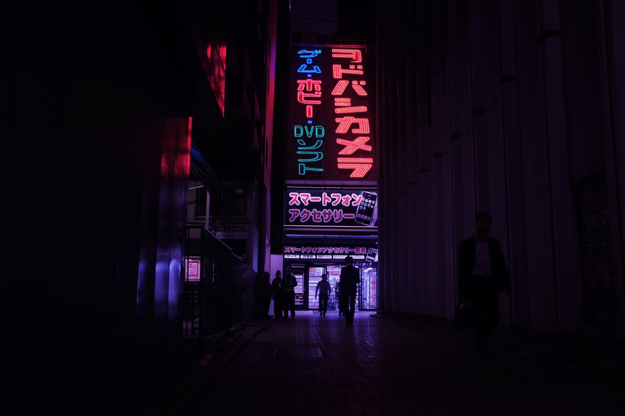 colorful neon signs illuminate a busy tokyo street at night showcasing