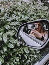 Young woman taking photo in mirror of car