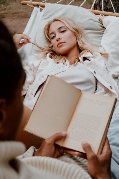 Free Photo of a Woman Lying Near a Person Reading a Book Stock Photo