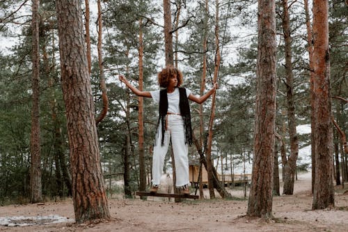Young Woman Standing on a Swing Suspended Between Trees in the Forest