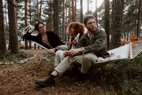 Free Group of friends enjoying leisure time in hammocks amidst a forest setting. Stock Photo