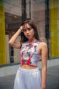 Woman in White and Red Tank Top Standing Near Glass Window