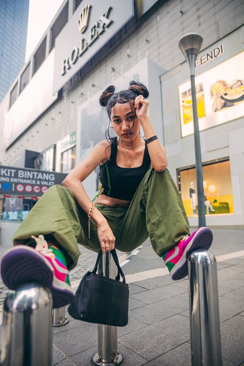 Free Stylish woman confidently posing on street bollards in urban setting. Stock Photo