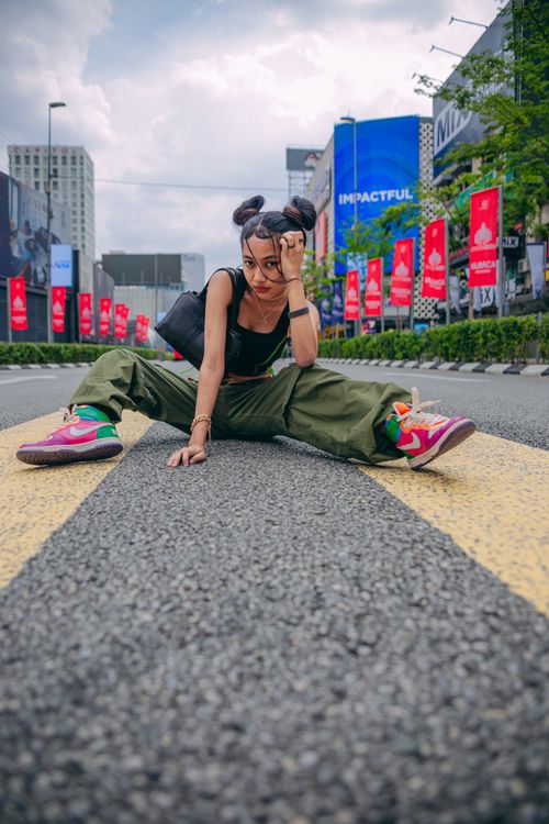 Free Stylish woman in colorful sneakers and chic outfit posing confidently on a city road. Stock Photo