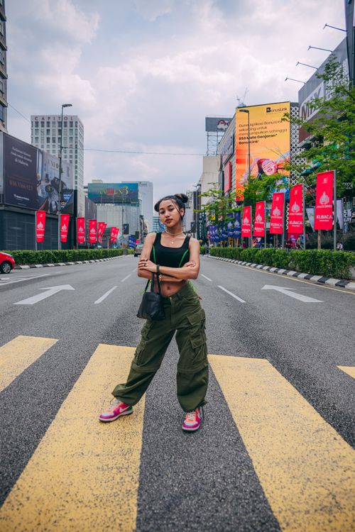 Free Fashionable woman posing confidently on a bustling city street lined with billboards. Stock Photo