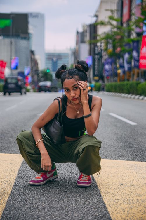 Free Young woman posing fashionably on a city street, showcasing modern urban style. Stock Photo