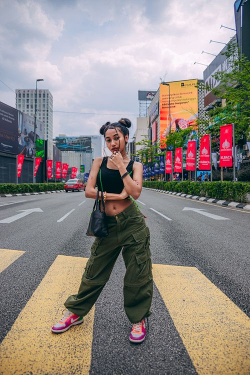 Free Fashionable woman poses confidently on a city street, showcasing urban style and charm. Stock Photo