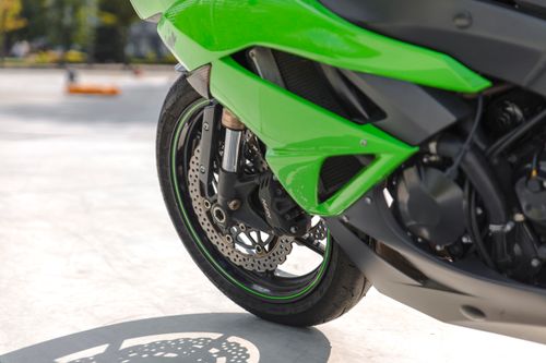 Free Detailed close-up of a green sport motorcycle's front wheel on a sunny day. Stock Photo