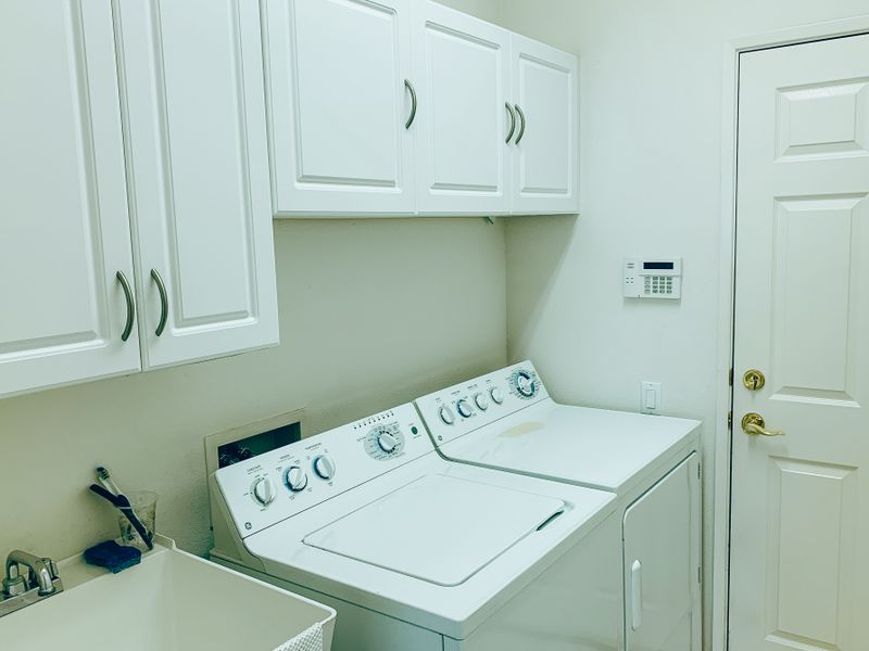 Testing a repaired dryer Organized laundry space with a washer, a dryer, and white cabinets