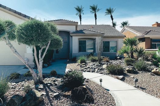 Stylish family home with xeriscape landscaping and palm trees under a bright sky.