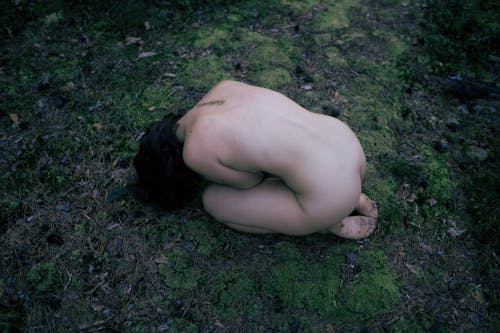 Free From above of anonymous nude female with bare feet lying on grassy ground Stock Photo