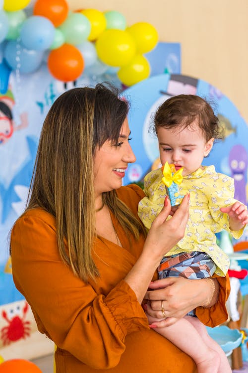 Photo of a Mother Showing a Toy to Her Child