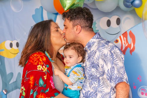 Couple Kissing While Holding Their Baby Between Them 