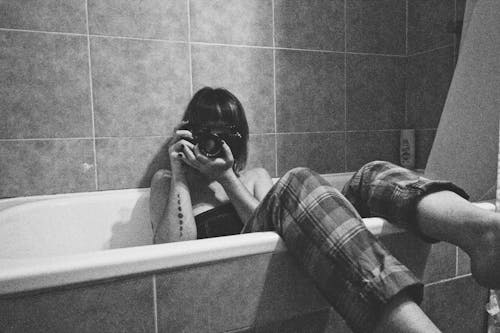 Woman Sitting in Bathtub and Photographing