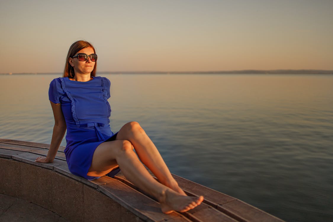 Woman in Blue Dress Sitting on Dock
