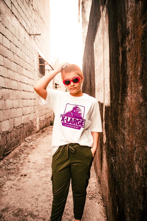 Free Stylish woman wearing sunglasses standing confidently in a narrow urban alley. Stock Photo