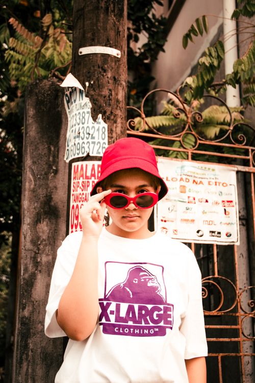 Free Casual portrait of a woman in red sunglasses and bucket hat in an urban outdoor setting. Stock Photo