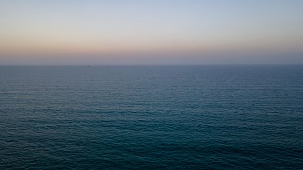 A tranquil aerial view of the calm ocean at dusk with a peaceful horizon.