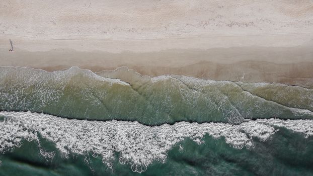 宁静的海滩景观自上而下，海浪轻拍着沙质海岸