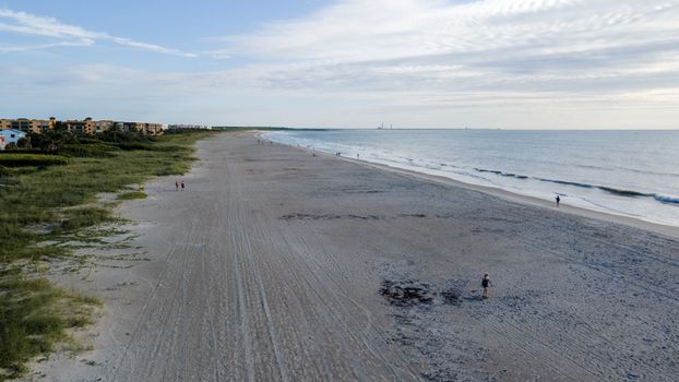 Aerial view of a tranquil beach scene with distant people and gentle waves.