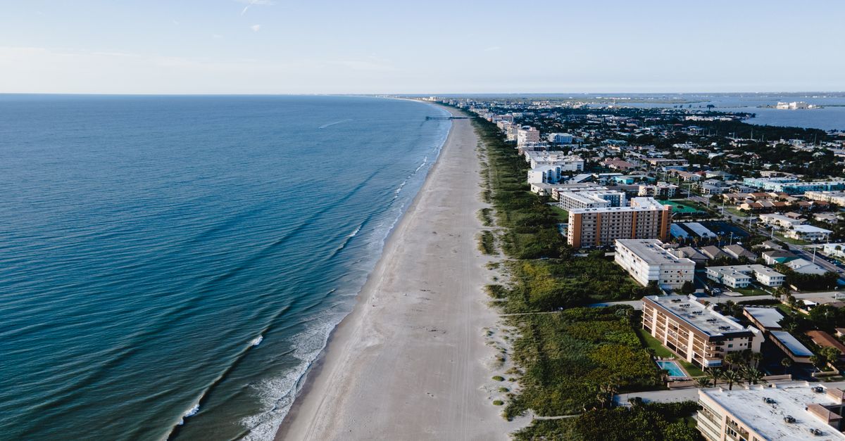 A stunning aerial view of a seaside city with sandy beaches and urban waterfront buildings.