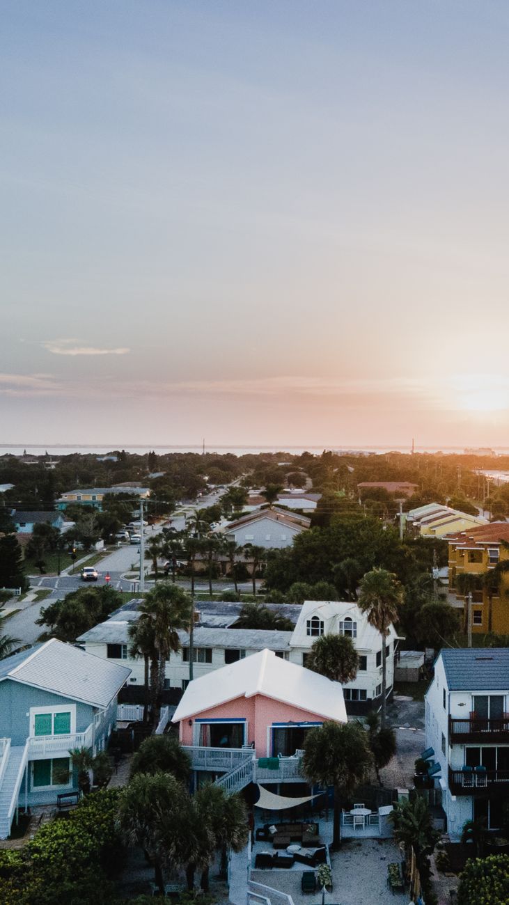 Aerial view of a residential neighborhood at golden hour with a service van on the street