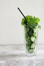 一个高玻璃杯里装满了新鲜的黄瓜片、生菜和其他蔬菜，准备用来榨汁