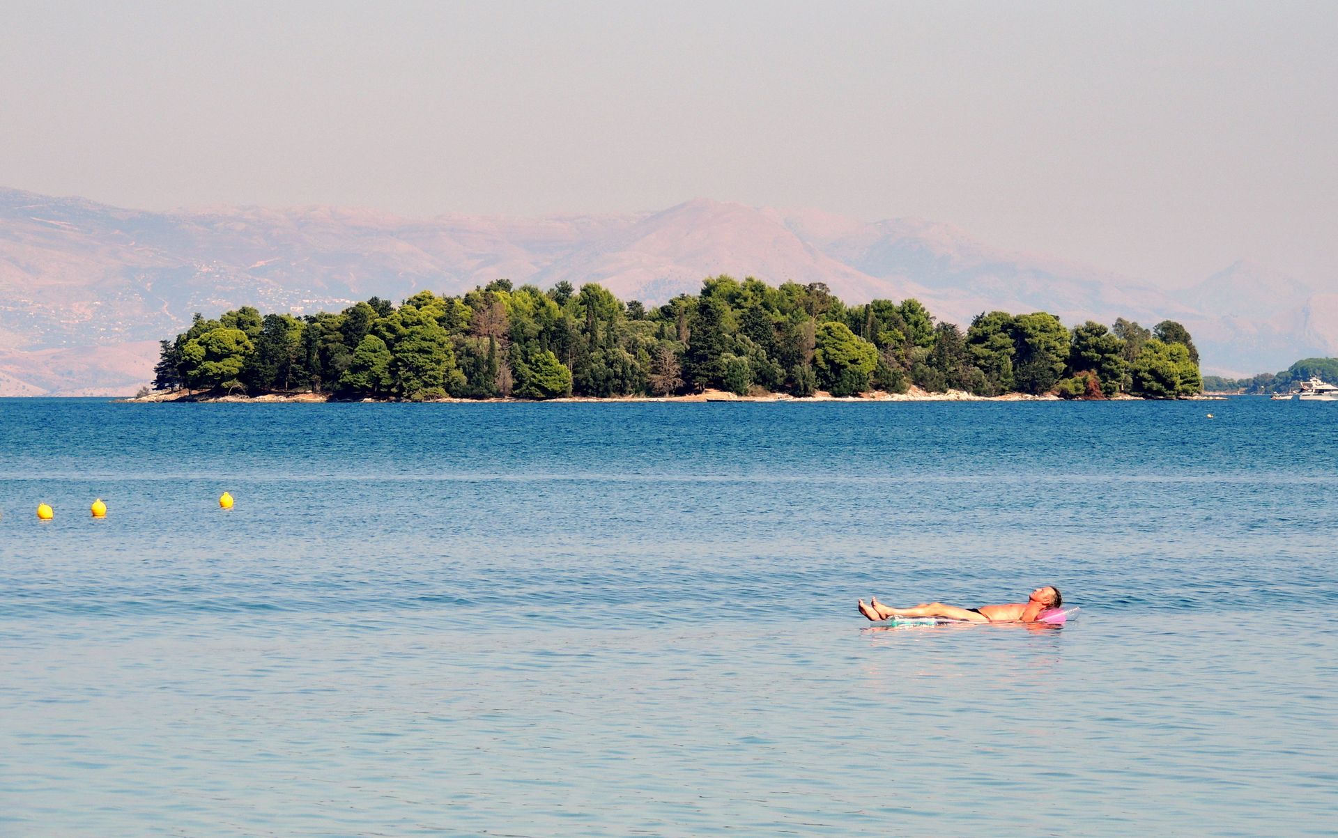 Adult male floating on air mattress near Kontokali, Greece's serene waters.