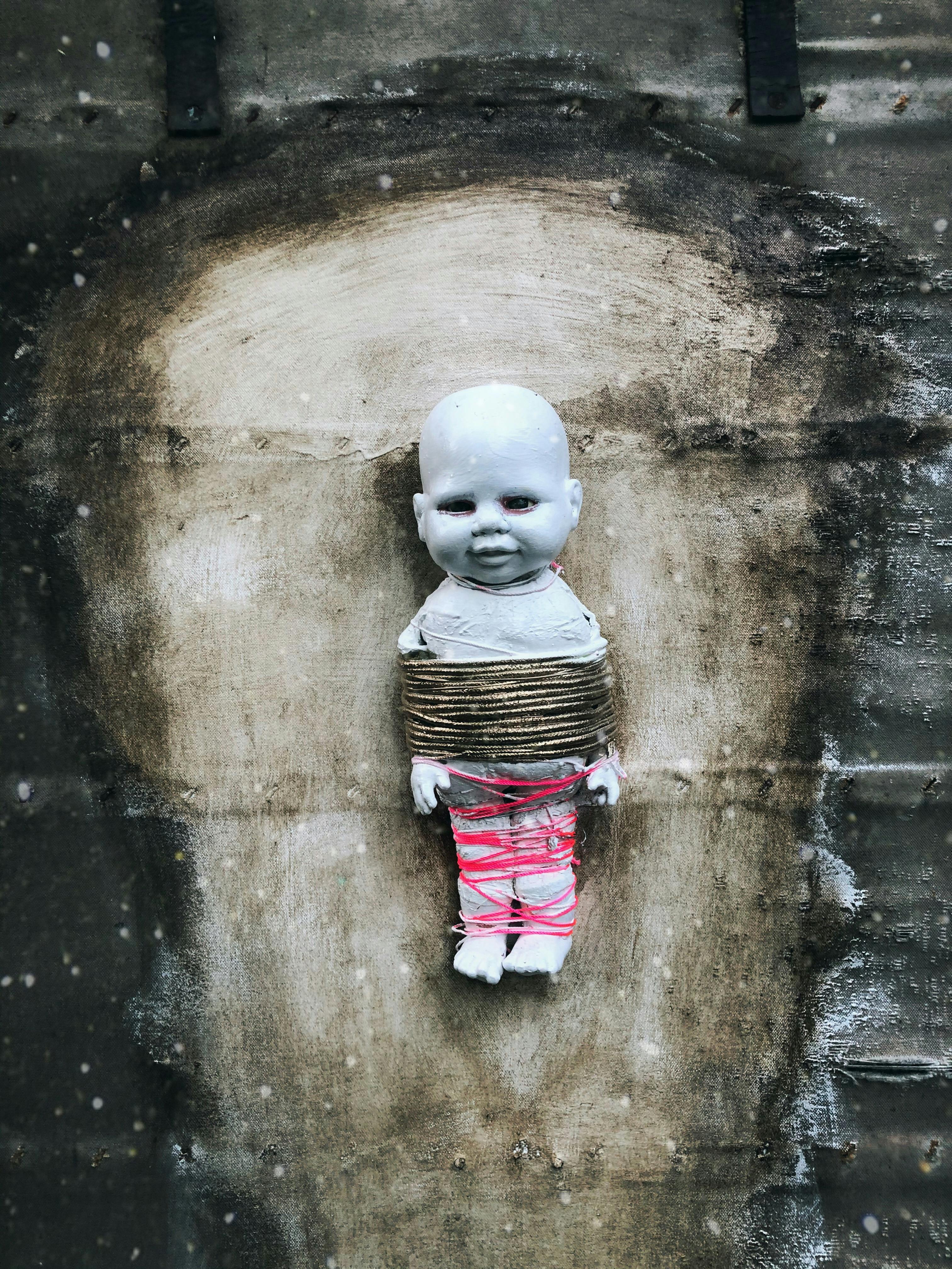 creepy doll tied to wall